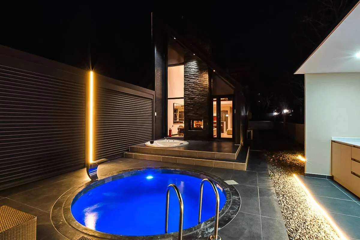 Gece aydınlatmalı yuvarlak havuz ve villa terası